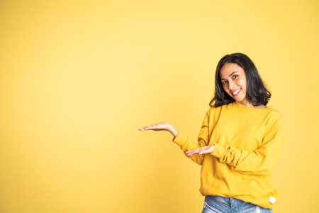 Young asian woman with hand gesture presenting something on isolated backgroundの写真素材