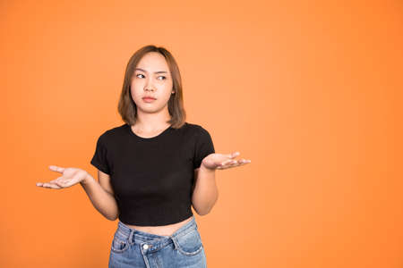 woman opening two palms does not know what to do on isolated background feeling uncertainの写真素材