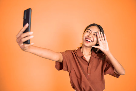 young woman make a video call using mobile phone with saying hello gesture on isolated background