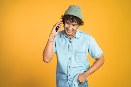 portrait of asian young man laughing while making phone call on isolated background