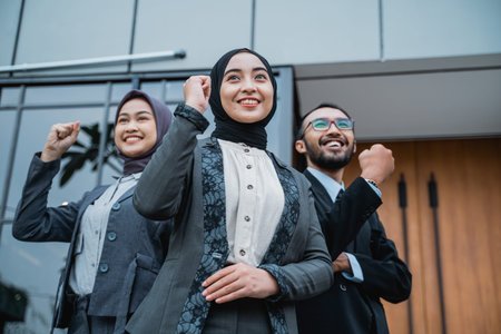 excited muslim businesswoman wearing hijab raise their arm showing success and winning gesture