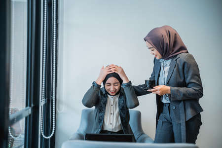 muslim female worker comforting her partner during hard time. business and working problem at the office. stress and work pressure of businesswomanの写真素材