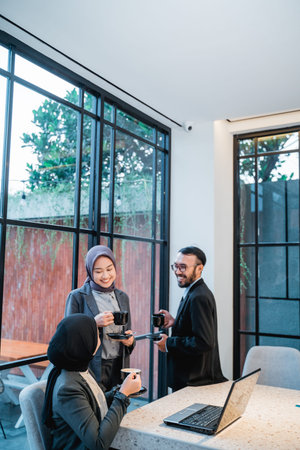 relaxed business meeting at the office while drinking coffee. asian muslim team having conversation...