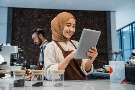 muslim female Cafe owner use tablet while working on her storeの写真素材