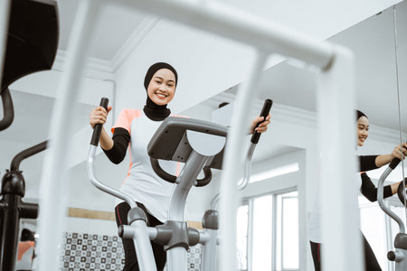 smiling beautiful women at the gym doing exercises on static elliptical cycle machine