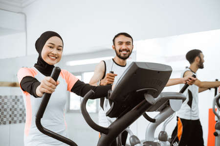 muslim women at the gym doing cardio exercises on static elliptical cycle machineの写真素材