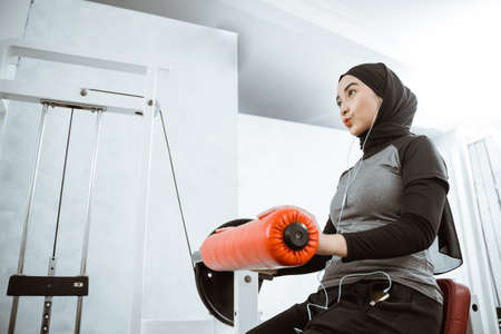 muslim asian woman working on her lower body using leg machine at the gymの写真素材