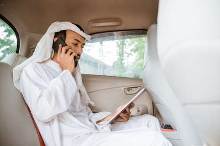 young man in a turban is calling using a mobile phone while sitting on his carの写真素材