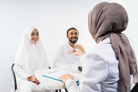 Doctor asks the husband and wife of prospective Hajj pilgrims during consultation in the roomの写真素材