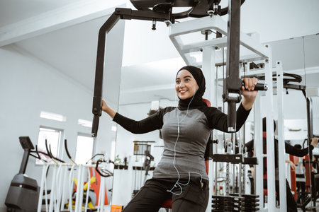 muslim asian woman using chest press machine during fitness at the gymの写真素材