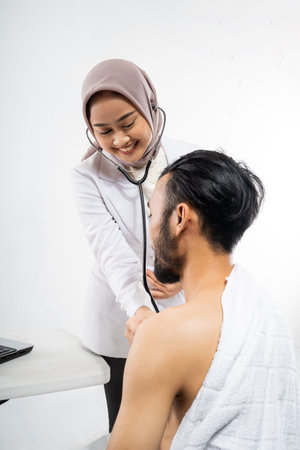 Female doctor using a stethoscope examining male prospective Hajj pilgrims on isolated background