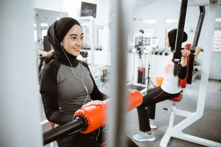 muslim asian woman working on her lower body using leg machine at the gymの写真素材