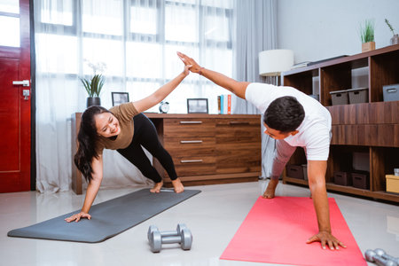 Asian fitness couple, man and woman exercising together at home doing partner workout push up and...