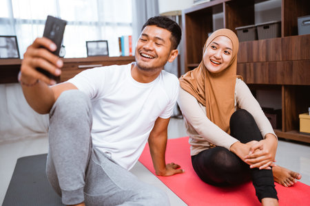 muslim couple using mobile phone together after exercising at home