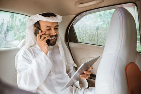 young man in a turban is calling using a mobile phone while sitting on his carの写真素材