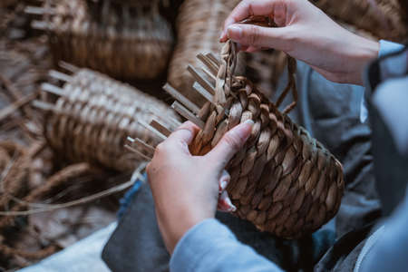 close up of craftswoman hands weaving water hyachinths while making craftsの写真素材