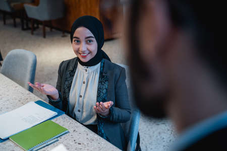 muslim manager and employee talking about the document in the office together while meetingの写真素材