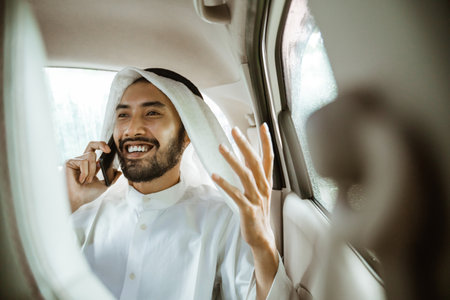 young man in a turban is calling using a mobile phone while sitting on his carの写真素材