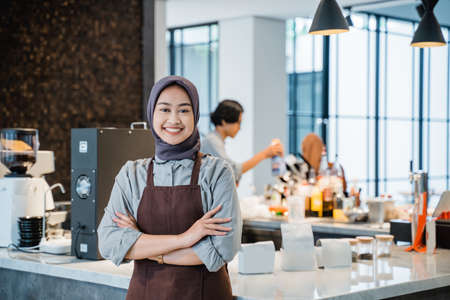 beautiful asian muslim woman crossed arm while standing in front of coffee shopの写真素材