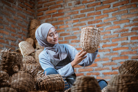 craftswoman in veil looking at woven water hyacinth crafts in brick houseの写真素材