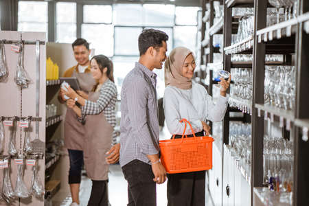 Muslim woman holding glass carrying basket and shopping with boyfriend in houseware storeの写真素材