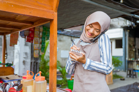 beautiful muslim seller taking order from customer through phone