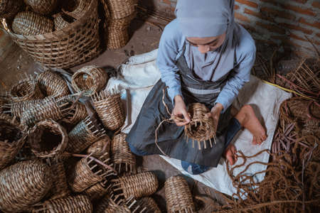 top view of a water hyacinth craftsman hijab woman weaving baskets indoorsの写真素材