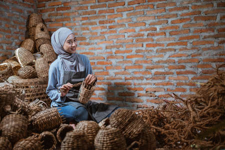 craftswoman in veil smiling weaving crafts woven water hyacinth in a brick houseの写真素材