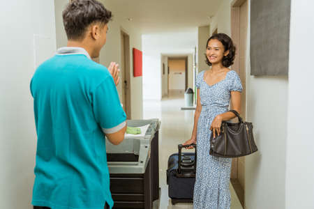 janitor with a greeting gesture when passing a female guest in the hotel hallwayの写真素材