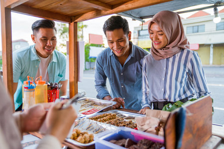 portrait of friend eating out together at traditinal food stall during lunch break