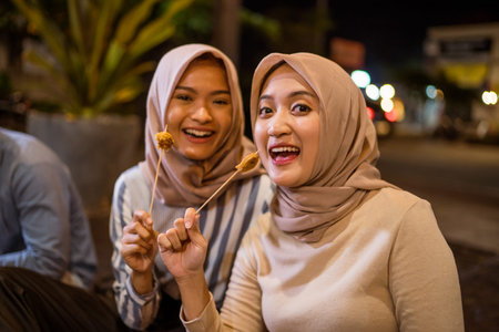 muslim friend eating satay break fasting in traditional food market stall