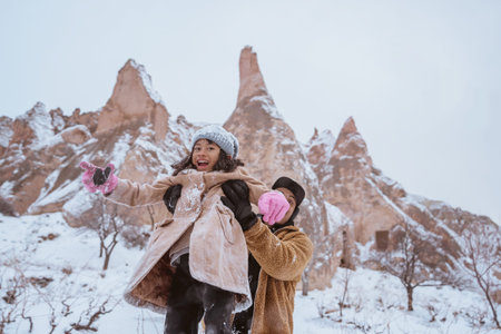 father giving piggyback ride to his daughter while playing outside in the snow