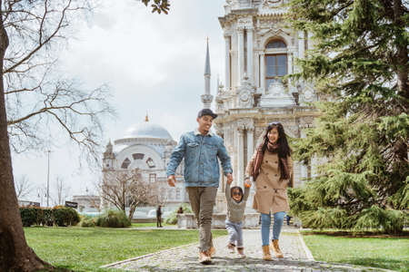 parent walking and playing with daughter while visiting turkey on holiday vacation with mosque at the backgroundの写真素材