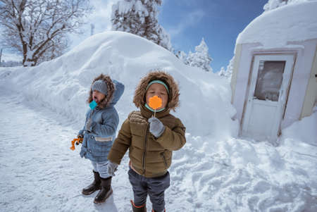 cute kid portrait close up while enjoying lollipop outside during snowy winterの写真素材