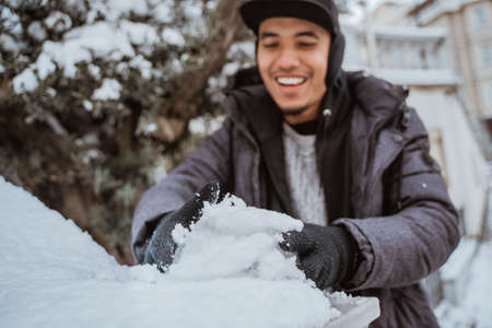 happy young man touching snow for the first time during visiting european countryの写真素材