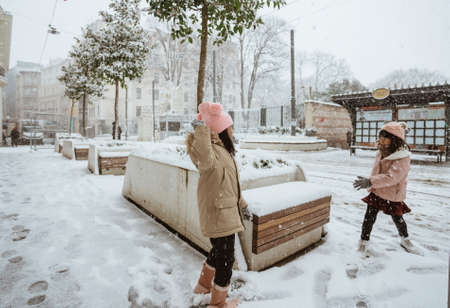 two little girl fighting snow ball in the city during winterの写真素材
