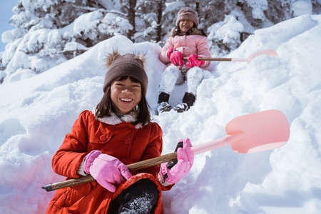 two girl playing with snow. asian little sister enjoy their time in snowy winter togetherの写真素材