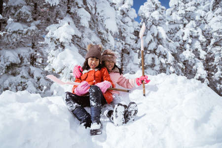 two girl playing with snow. asian little sister enjoy their time in snowy winter togetherの写真素材