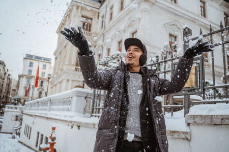 happy young man touching snow for the first time during visiting european countryの写真素材