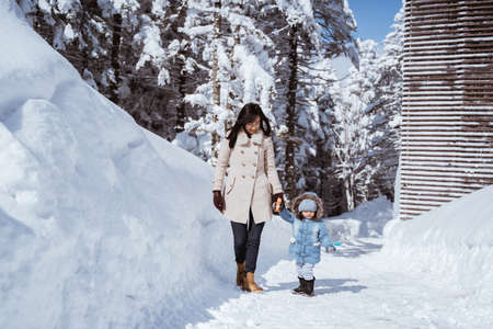portrait of a mother walking with her kid in snowy mountainの写真素材
