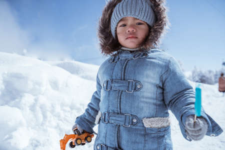 cute little kid walking alone in the middle of snowy mountainの写真素材