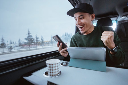 busy young man working while going out by a van. male business using mobile phone and tablet while...