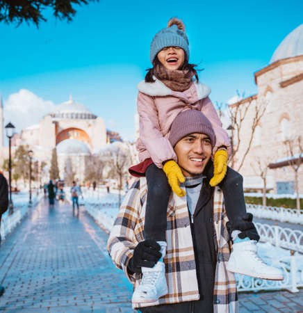 father carrying her daughter in his shoulder while visiting hagia sophia mosque in winter holidayの写真素材