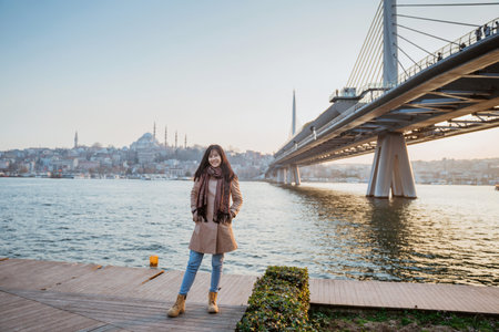 young girl relaxing on the side of bosphorus during sunset. beautiful woman with istanbul city scape at the backgroundの写真素材