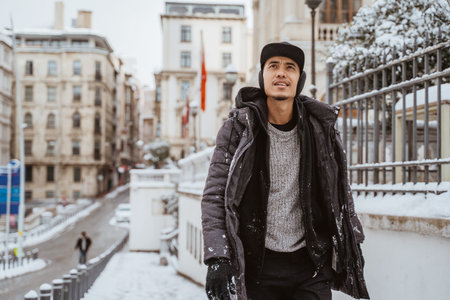 asian man walking in historical old town in istanbul during snow winter seasonの写真素材