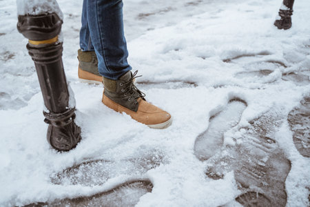 close up of mans shoes stepping on a snow on the street