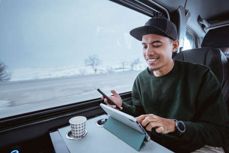 busy young man working while going out by a van. male business using mobile phone and tablet while travelingの写真素材