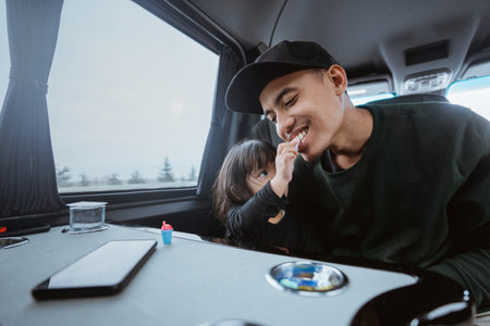 father and daughter having fun during their journey inside a moving vanの写真素材
