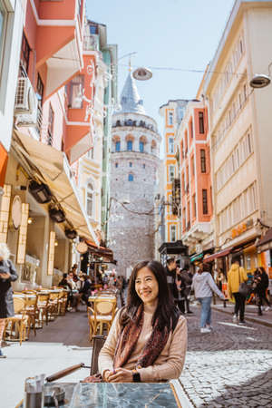 beautiful asian woman enjoy drinking a cup of coffee while sitting in historical city of istanbul with galata tower in the backgroundの写真素材