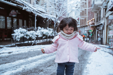 cute little girl in the city cover with snow during winterの写真素材